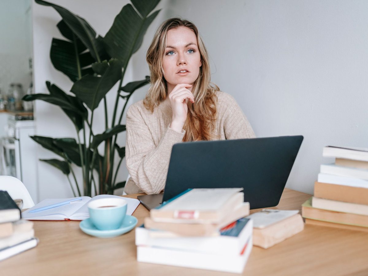 A woman at a laptop at home, thinking something over